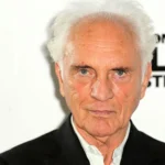 Terence Stamp in a sharp suit, his piercing gaze and sculpted features illuminated by soft studio light, capturing the timeless charisma of the man who brought General Zod and countless unforgettable characters to life