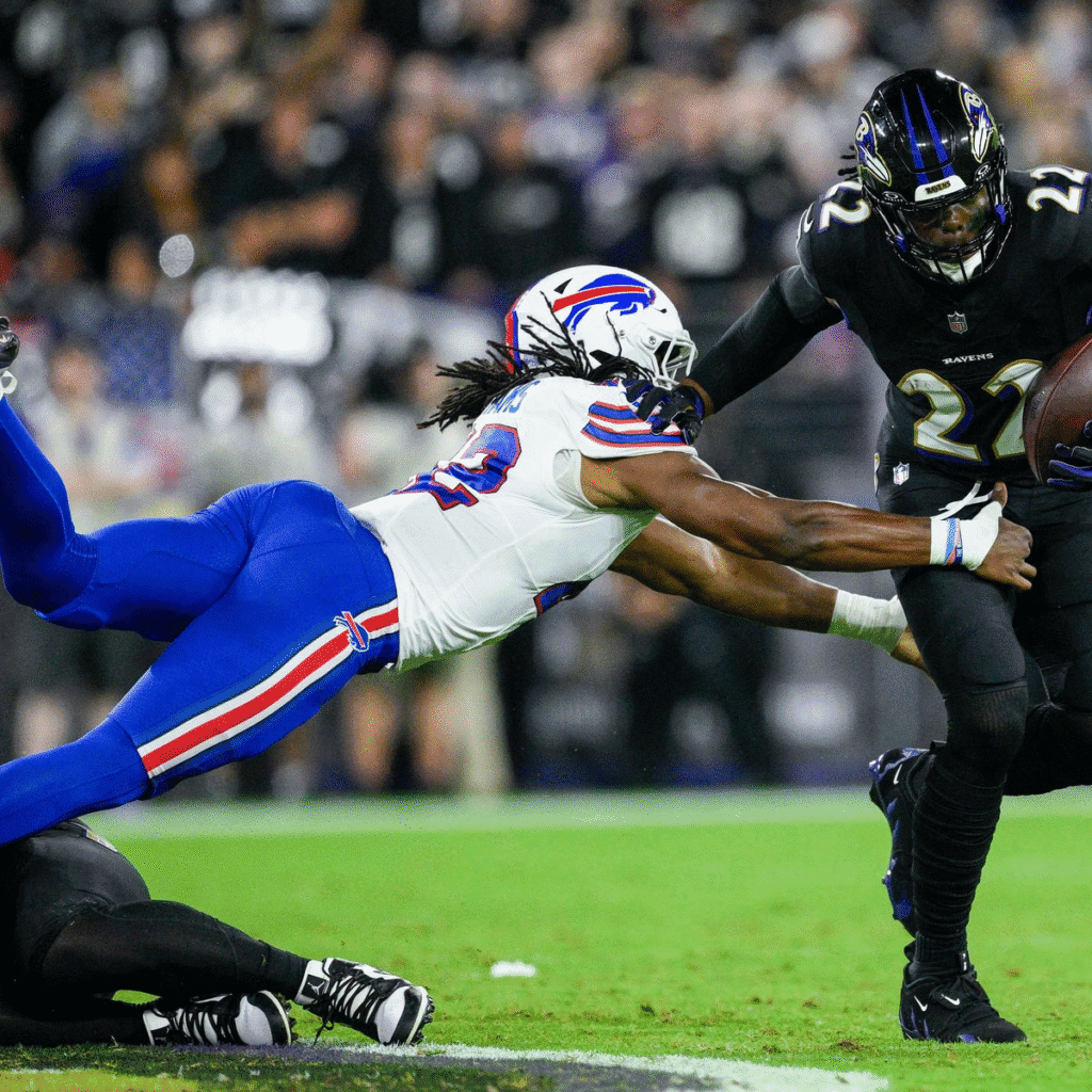 Baltimore Ravens player number 22 evades tackle from Buffalo Bills defender number 23 during NFL game action