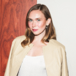 Image editing interface showing a professional portrait of Veronika Slowikowska, Canadian comedian and new SNL cast member, wearing a beige blazer against a wood-paneled background